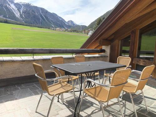 a table and chairs on a balcony with mountains at Ferienwohnung Jalet in Tschierv