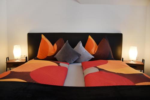 a bed with colorful pillows on it with two lamps at Haus Christina in Weissensee
