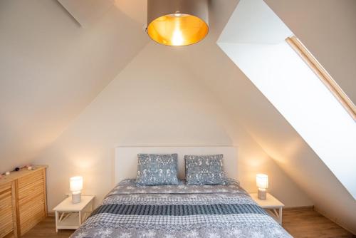 a attic bedroom with a bed and two lamps at Rainbow Palanga in Palanga