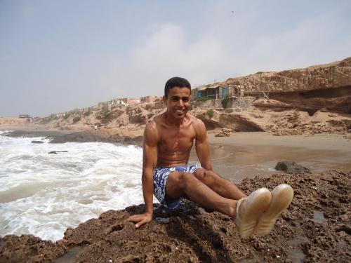 a man sitting on a rock on the beach at Takad Dream Rural in Takate
