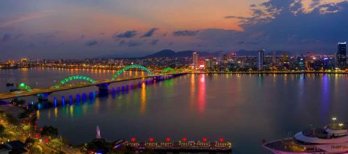 a bridge over the water with a city at night at Benzen Boutique Stays in Danang