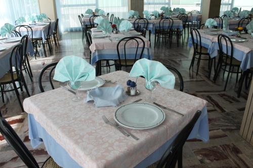 a dining room with tables and chairs with plates and napkins at Hotel San Paolo in Rimini