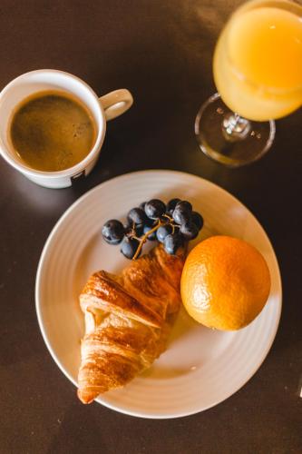 a plate with a croissant and oranges and a cup of coffee at Hôtel-Restaurant Bois Joly in Crozet