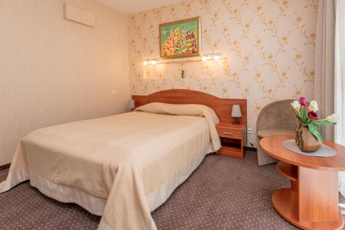 a bedroom with a bed and a table with a vase of flowers at Vila Vitalija in Palanga
