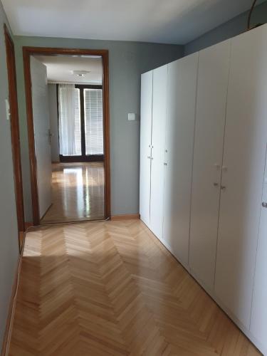 Ein leerer Raum mit weißen Schränken und einem Hartholzboden in der Unterkunft Paradise in Vrnjačka Banja