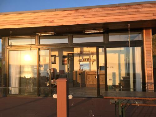 a glass house with a deck with the sun setting at Loughanmore Court Beach house in Dundalk
