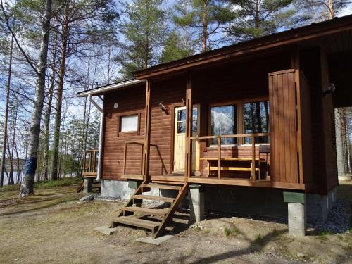 a wooden cabin in the woods with a porch at Lomasaaret Cottages in Villala
