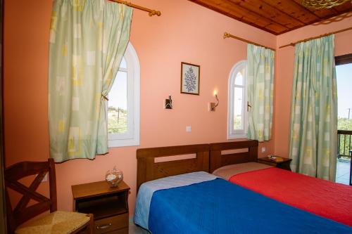 a bedroom with two beds and two windows at Dionysia's Apartments in Tsilivi