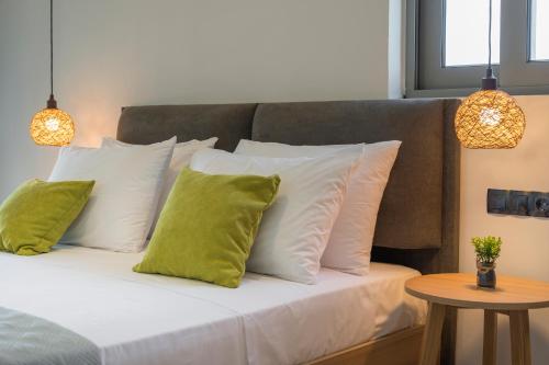 a bed with white pillows and green pillows at Aegean Breeze Luxury Apartments next to the sea in Maleme