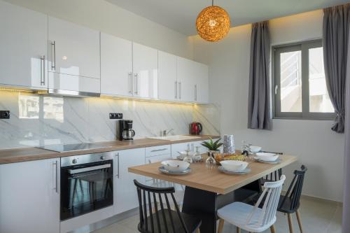 a kitchen with a wooden table with chairs and a tableasteryasteryasteryasteryastery at Aegean Breeze Luxury Apartments next to the sea in Maleme