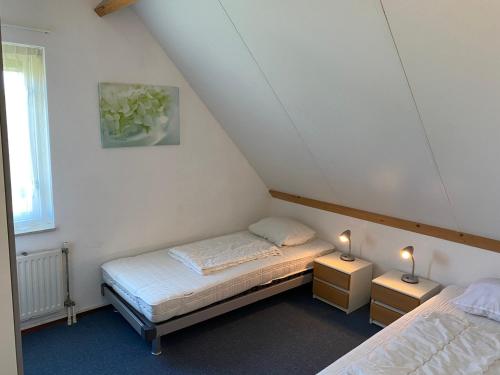 een kleine kamer met 2 bedden en 2 lampen bij Oesterbaai 35 in Wemeldinge