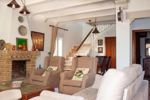 sala de estar con sillas y chimenea en Villas Dehesa Roche Viejo, en Conil de la Frontera