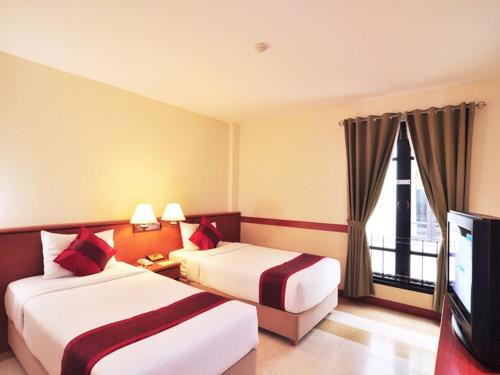 a hotel room with two beds and a flat screen tv at The Ecotel Bangkok in Bangkok