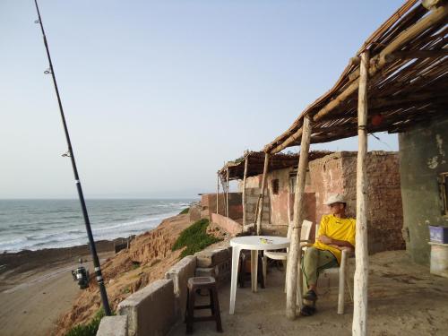 a man sitting at a table next to the beach at Takad Dream Rural in Takate