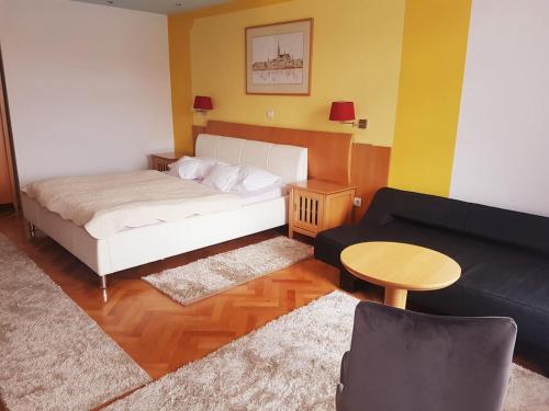 a bedroom with a bed and a couch and a table at Hotel Millennium in Osijek