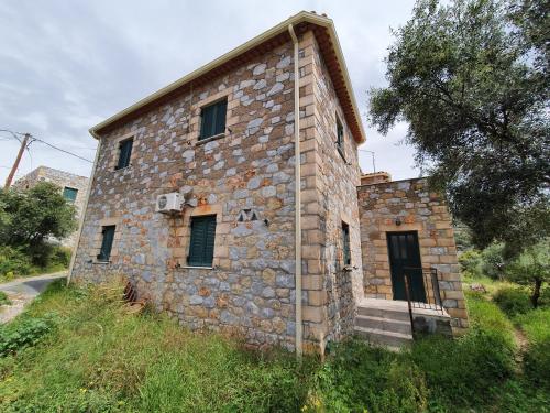 an old stone building on the side of a hill at Frigano 2 in Stoupa