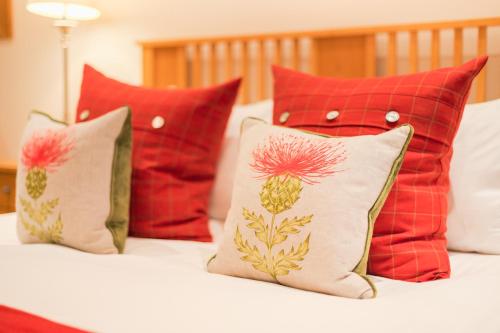 a group of pillows on a bed with red pillows at Highland Apartments by Mansley in Inverness