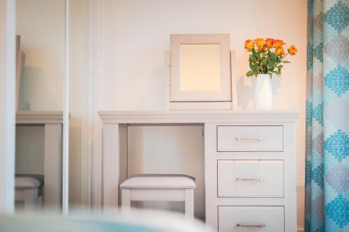 a dressing table with a vase of flowers and a mirror at Highland Apartments by Mansley in Inverness