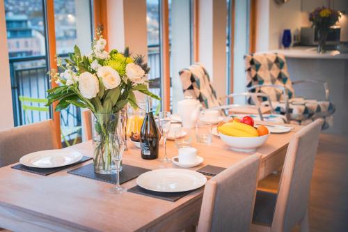 a wooden table with a vase of flowers on it at Highland Apartments by Mansley in Inverness