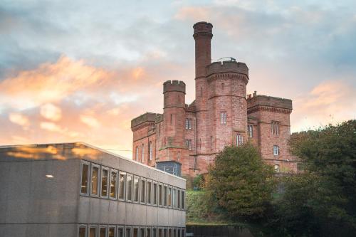 an old castle with two chimneys on top of a building at Highland Apartments by Mansley in Inverness