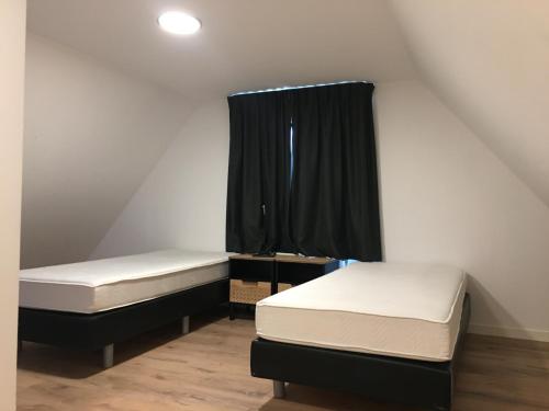 2 łóżka w małym pokoju z czarną zasłoną w obiekcie Appartement Buiten de Veste 28 w mieście Veere
