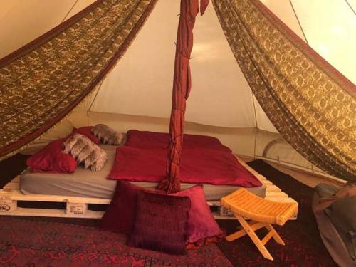 a bed in a tent with red sheets at Into the Green Glamping - Chestnut in Markt Nordheim