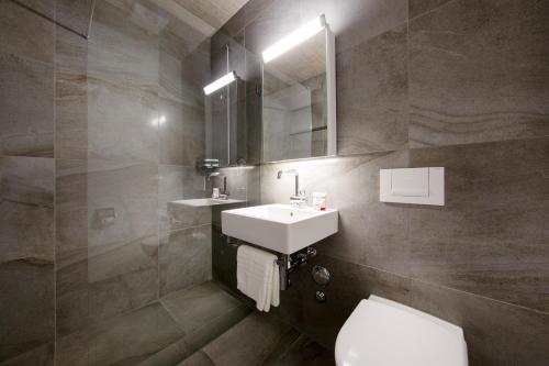 a bathroom with a sink and a toilet and a mirror at Nest - Kanzleistrasse 225 in Zurich