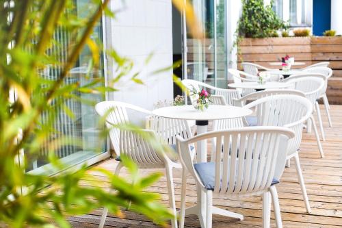 a row of white tables and chairs on a patio at fjord hotel berlin in Berlin