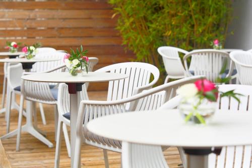 a row of white tables and chairs with flowers on them at fjord hotel berlin in Berlin