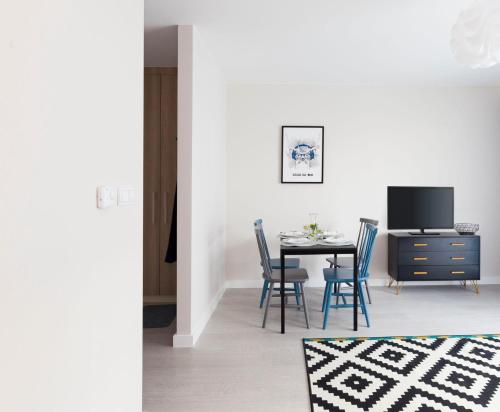 a dining room with a table and chairs and a tv at Raval Apartments - Soft Black in Rewal