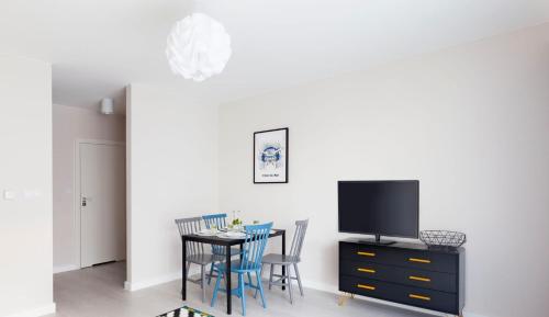 a dining room with a table with chairs and a tv at Raval Apartments - Soft Black in Rewal