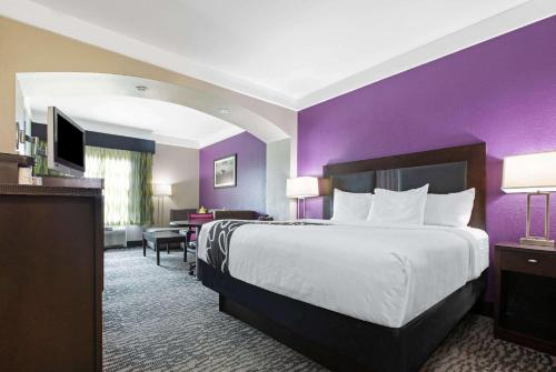 a hotel room with a bed and a purple wall at La Quinta by Wyndham Pearland in Pearland