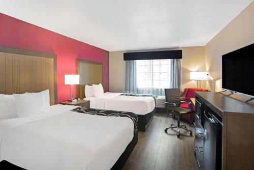 a hotel room with two beds and a flat screen tv at La Quinta by Wyndham Fort Smith in Massard
