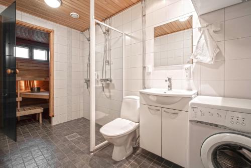 a bathroom with a toilet and a sink and a washing machine at Ski-Inn MastonAitio in Ruka