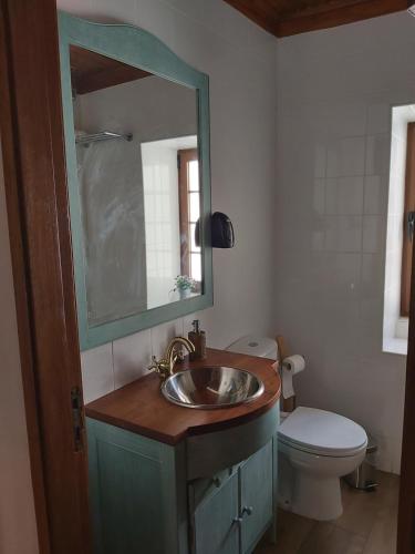 een badkamer met een wastafel, een toilet en een spiegel bij Casa da Souropires in Pinhel