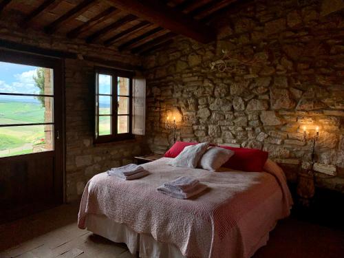 a bedroom with a large bed in a stone wall at The Lazy Olive Villa - Podere Finerri in Asciano
