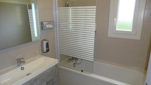 a white bathroom with a sink and a shower at Logis Hotel des Granges in Arles