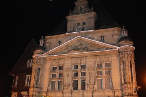 a large building with a clock tower at night at Chambres d'Hotes Noir Lion in Péronne