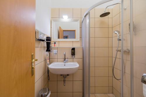 ein Bad mit einem Waschbecken und einer Dusche in der Unterkunft Parlamento Rooms in Berlin