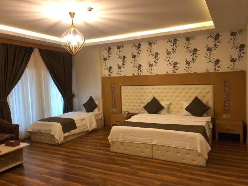 a bedroom with two beds and a chandelier at Classy Hotel Erbil in Erbil