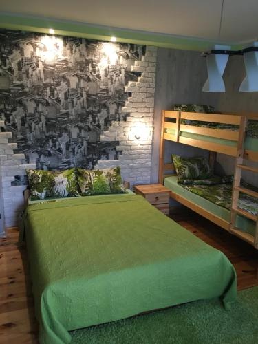 um quarto com uma cama verde e uma parede de tijolos em Pie ābeles em Ventspils