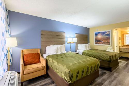 a hotel room with two beds and a chair at Quality Inn New Orleans I-10 East in New Orleans
