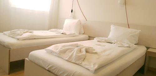 two beds in a room with white sheets on them at Easy-Living Apartments Lindenstrasse 48 in Lucerne