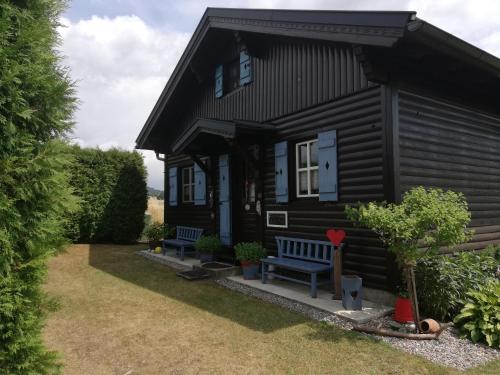 a black house with two benches in front of it at Ferienhaus Ulli in Gansbach
