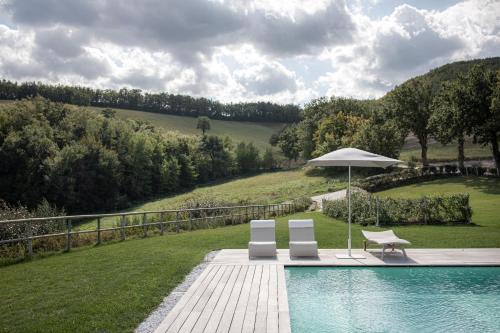 two chairs and an umbrella next to a swimming pool at Agriturismo Colle Casini Cortesi in Caldarola