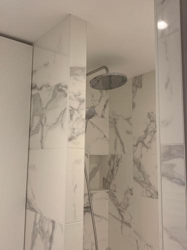 La salle de bains est pourvue d'une douche et de murs en marbre. dans l'établissement Celect'In Lyon Suites climatisées SkyView, à Lyon