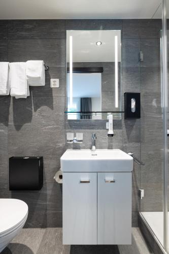 a bathroom with a sink and a toilet and a mirror at B&B Hotel Mattli Übernachtung Frühstück in Morschach
