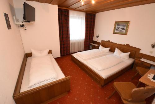 a room with two beds and a desk and a tv at Hotel Klausen in Pill