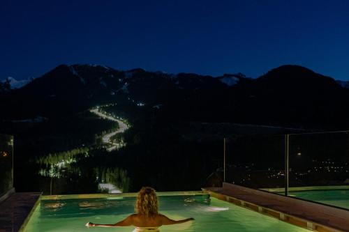 a woman in a swimming pool at night at La Roccia Wellness Hotel in Cavalese