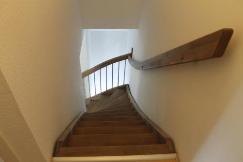 a staircase in a building with a wooden rail at Haus Seesturm in Neßmersiel